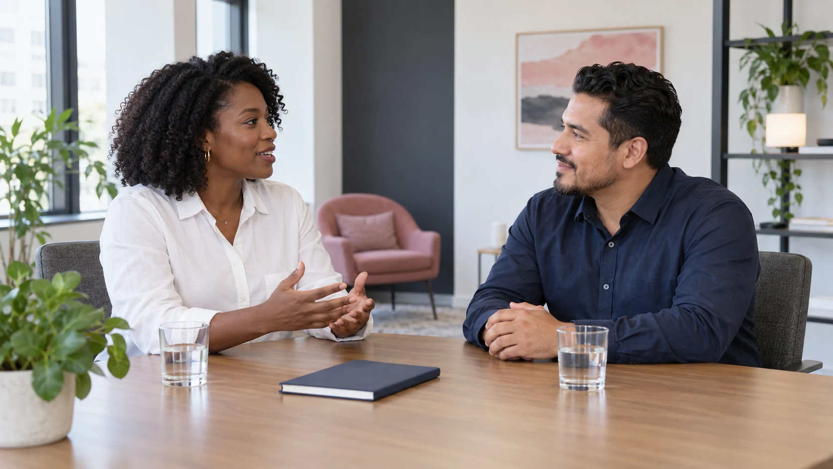 Two colleagues practicing a conversation with a notebook resting flat on the table